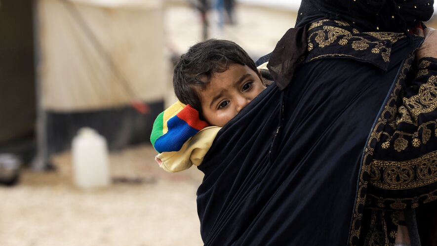 A displaced Syrian child, fleeing from Deir Ezzor besieged by Islamic State (IS) group fighters, hangs on the back of a woman as she walks through a refugee camp in al-Hol, located 14 kilometers from the Iraqi border in Syria's northeastern Hassakeh province, February 1, 2017. Photo by: DELIL SOULEIMAN/AFP/Getty Images