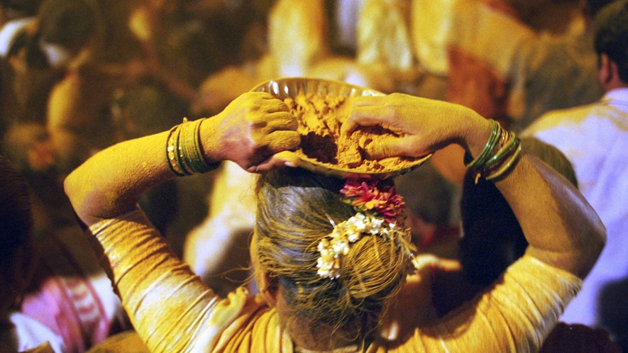 A woman at a Hindu festival throwing yellow turmeric, Mumbai, India, February 2003. Photo by: Martin Godwin/Getty Images.