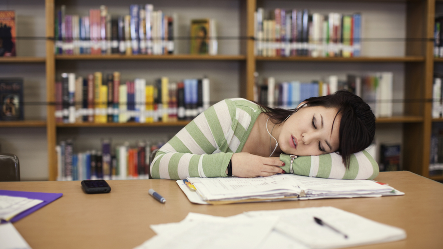 A teenager falls asleep in a library. Photo from Getty Images